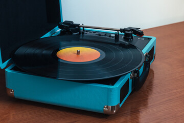 Horizontal photo of a vinyl on a blue turntable on a wooden table. Concept hobbies, art.