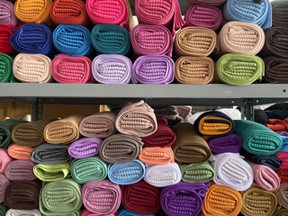 Stacks of hijabs, headscarves of various colors in rolls, photos of piles of colorful hijabs rolled...