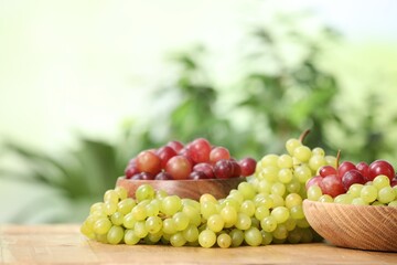 Different fresh ripe grapes on wooden table. Space for text