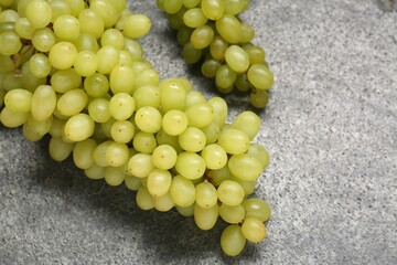 Delicious fresh green grapes on grey textured table, above view