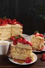 Tasty cake with fresh strawberries, mint and cup of drink on wooden table
