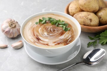 Delicious cream soup with soy sauce and parsley served on light grey marble table