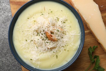 Delicious cream soup with parmesan cheese and croutons in bowl on grey table, top view