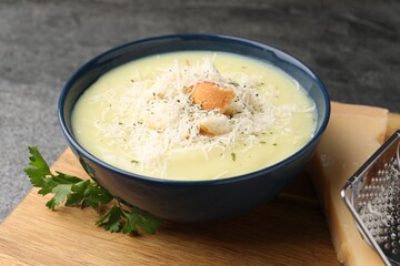 Delicious cream soup with parmesan cheese and croutons in bowl on grey table, closeup