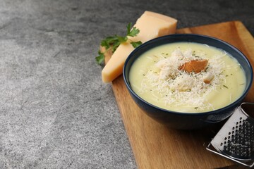 Delicious cream soup with parmesan cheese and croutons in bowl on grey table. Space for text