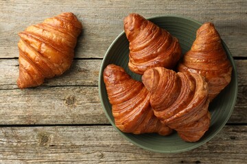Delicious fresh croissants on wooden table, flat lay