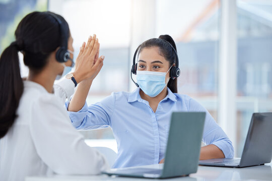 Covid face mask, high five and call center women in customer service laptop support, telemarketing success and b2b sales. Contact us, receptionist or consultants on office tech in covid 19 compliance