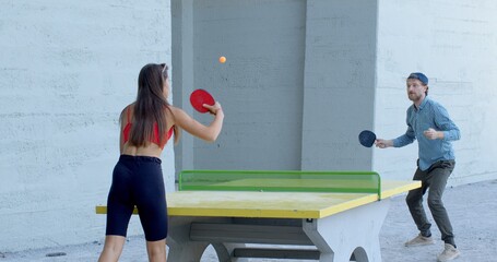 Couple is playing outdoor table tennis, enjoying an active and healthy lifestyle while having fun together. This sport combines physical activity, coordination, and friendly competition. 