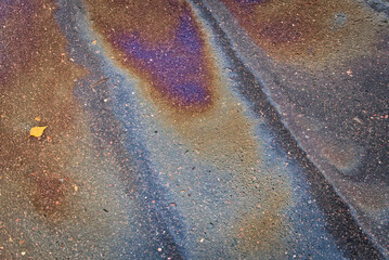 Colored texture of oil products on the asphalt in the rain.