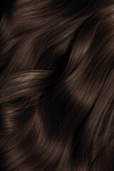 Brown hair close-up as a background. Women's long brown hair. Beautifully styled wavy shiny curls....