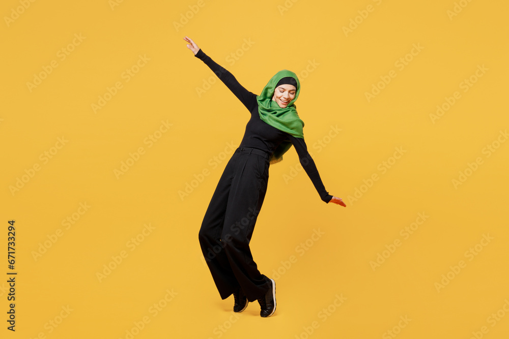 Wall mural full body young arabian asian muslim woman in green hijab abaya black clothes stand on toes with out