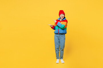 Full body young fun woman she wears padded windbreaker jacket red hat casual clothes point index...
