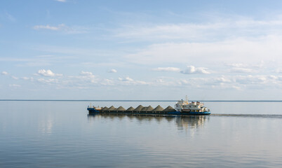 Obraz premium A dry cargo barge sails on Lake Beloe in complete calm