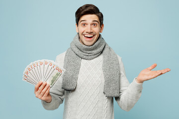 Young ill sick man wear gray sweater scarf hold fan of cash money in dollar banknotes isolated on...