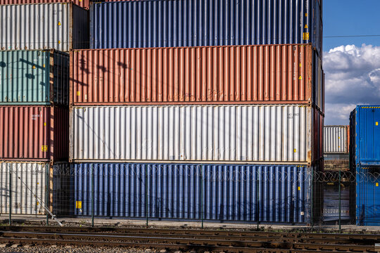 Colored stacked 40ft unmarked freight containers at a railway container terminal. Close-up. International cargo logistics