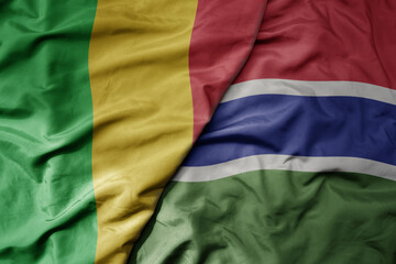 big waving national colorful flag of mali and national flag of gambia .