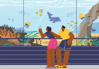 Young couple watching underwater life in oceanarium.