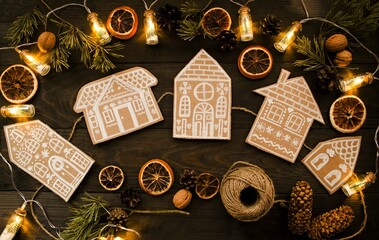 On a wooden background there is a craft made of cardboard, a garland of paper houses on a jute rope...