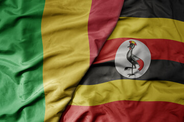 big waving national colorful flag of mali and national flag of uganda .