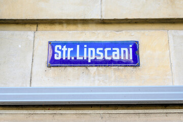 Naklejka premium Beautiful vintage street sign showing Strada Lipscani (Lipscani Street) displayed on an street in the old city center of Bucharest, Romania, in a sunny day with clear blue sky