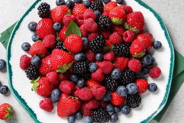 Different fresh ripe berries on light grey table, top view
