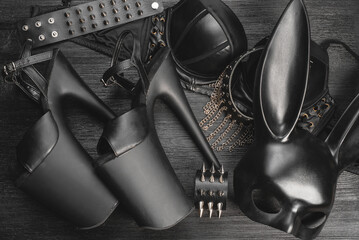 Black rabbit mask, studded leather bracelets and neck choker on the black wooden table background.