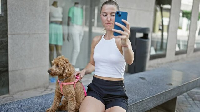 Young caucasian woman with dog taking selfie photo with smartphone sitting on bench at street