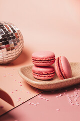 Italian macarons, disco ball and confetti hearts on a pink background, Valentine's Day vertical card with copy space