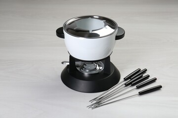 Fondue set on white wooden table. Kitchen equipment