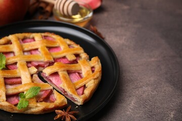 Delicious apple pie with mint on brown table, closeup. Space for text