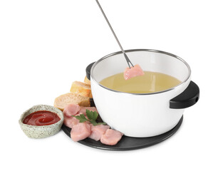 Dipping piece of raw meat into oil in fondue pot on white background