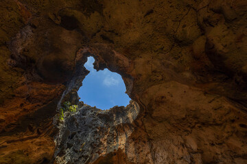 Stunning interior view of Quadirikiri Caves in Aruba National Park with captivating feature of hole in cave's ceiling that frames view of blue sky.