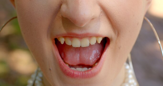 Close-up smile young woman mouth, lips and teeth close up. Lifestyle Fangs and teeth in a grin while playing to attract the attention of the opposite sex. Flirting concept