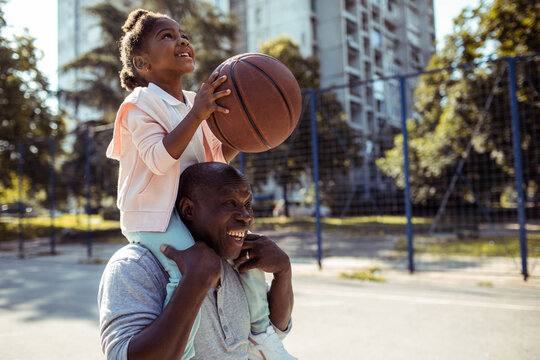 Grandfather playfully teaches his granddaughter how to handle a basketball