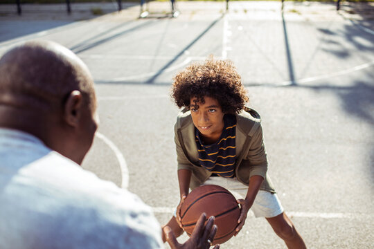 Young boy prepares to make a move in a friendly basketball game with his elder