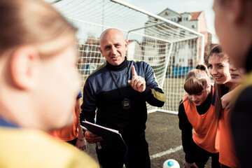 Dedicated coach offering guidance to his female soccer team during practice