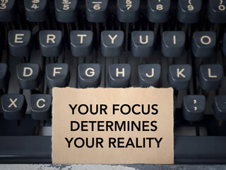 Motivational and inspirational wording. YOUR FOCUS DETERMINES YOUR REALITY written on a paper. With...
