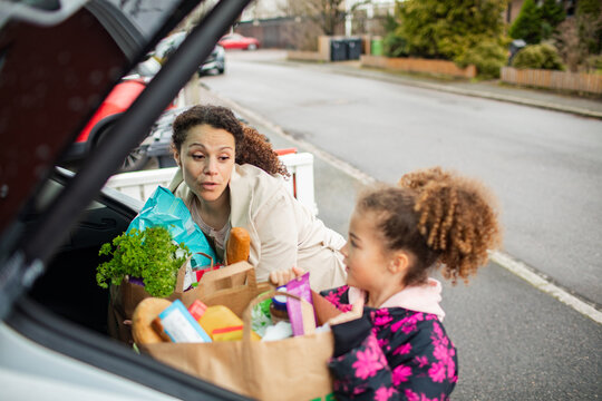 Mother and daughter unloading grocery shopping from their car