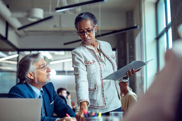 Senior colleagues discussing a document in a modern office setting