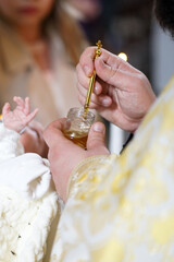 The priest performs the rite of anointing the newborn during baptism.
