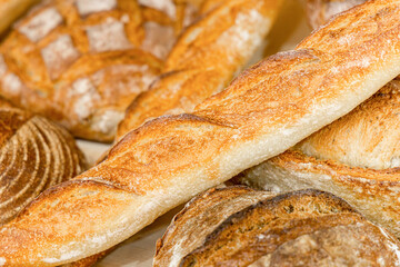 French baguettes and other baked goods on a shelf in a bakery. Fresh pastries, bakery products. Production and sale of bread products. Selected focus