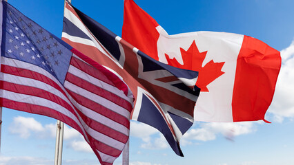 American Flag, Canadian Flag and Flag of Great Britain on blue sky