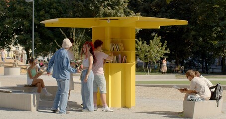 People rest in park, reading books. An open public library is a community resource that provides...