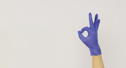 Hand wears a violet latex glove and do an OK sign.