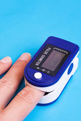 One pulse oximeter on finger on blue background