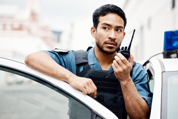 Asian man, police and walkie talkie for radio in city communication, reinforcement or emergency. Serious male person or security guard by cop car and calling backup for crime on patrol in urban town - obrazy, fototapety, plakaty