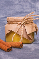 Jar of honey and cinnamon on gray background