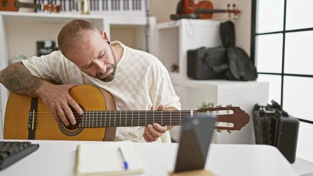 Young man recording video by smartphone playing classical guitar at music studio