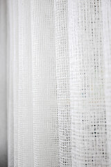White curtains in the form of a small mesh. Abstract background. Selective focus.