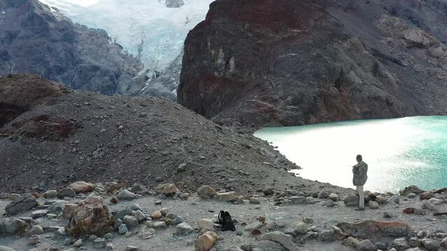 Dramatic drone scene of hiker exploring nature on the base of the Mount Fitz Roy, with the "Laguna de los tres"on the background and the mountains on parallax movement. Patagonia, Argentina